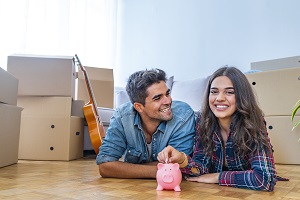 Young couple smiling on floor of their new house.